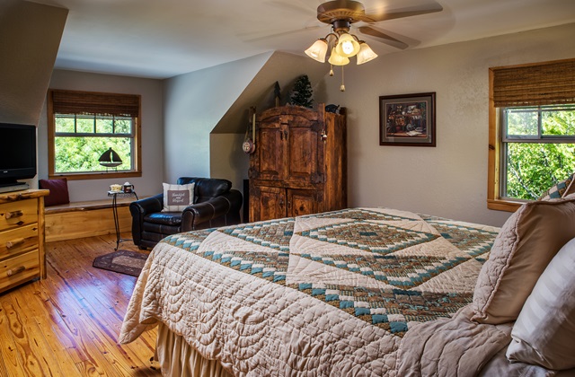 View from the Lakeview room looking at queen size bed, comfortable sitting chair, and reading lamp at Three Falls Cove